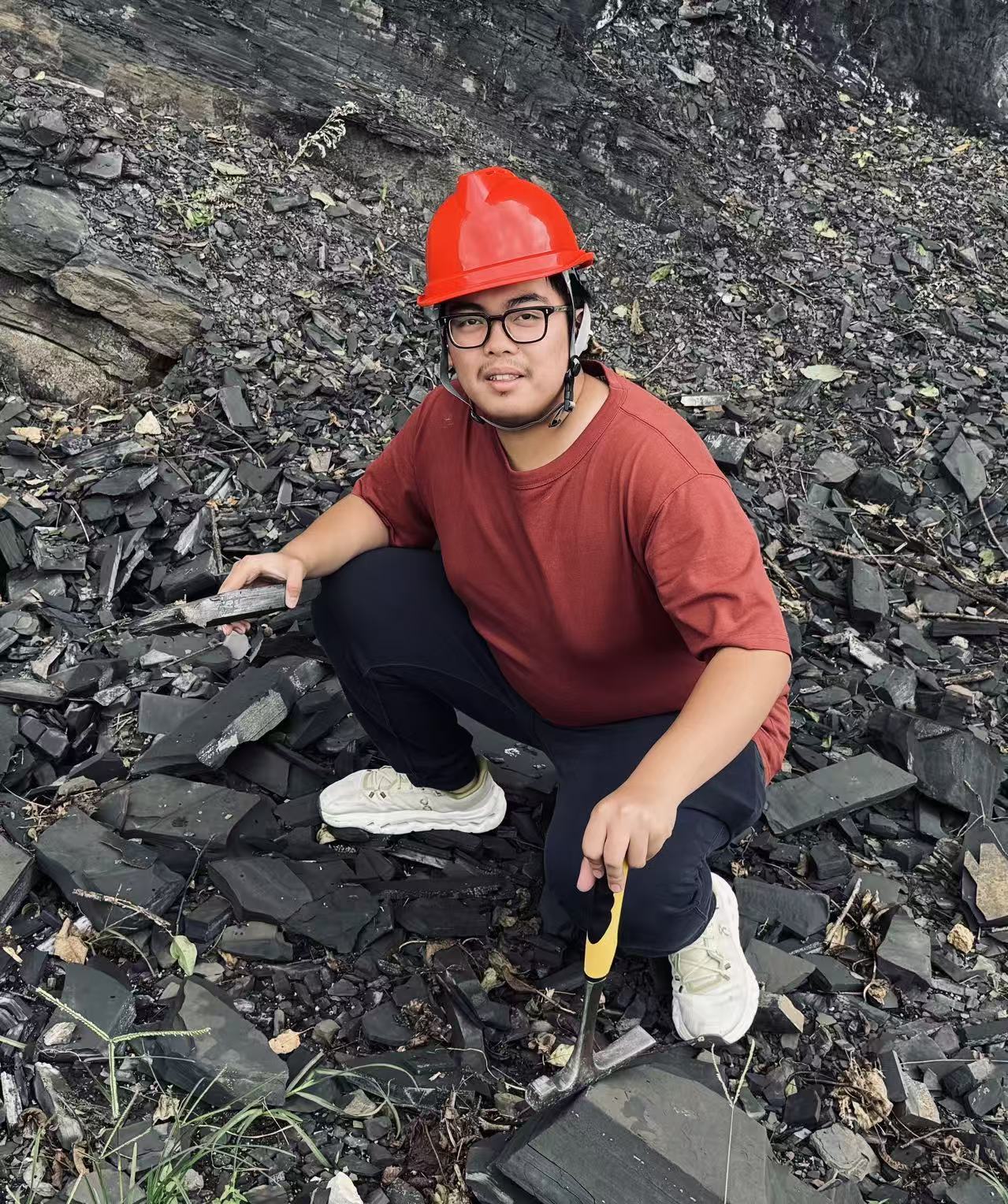 Li Zeyu at a shale outcrop with a rock hammer